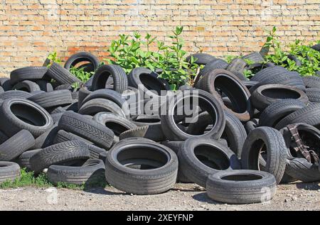 Schmutzige Autoreifen auf einer Müllhalde in der Stadt. Umweltverschmutzung durch die Industrie. Abkippen unnötiger Gummireifen in der Nähe einer Reparaturwerkstatt. Ökologische Situation Stockfoto