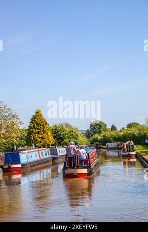 Mann und Frau auf einem gemieteten Kanalschnallbooturlaub, der durch Hassall Green auf dem Trent- und Mersey-Kanal, dem Kanal von Heshire, England, führt Stockfoto