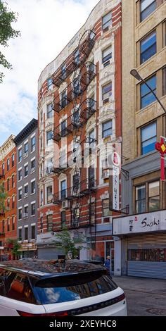 NYC Chinatown: 54 Eldridge Street ist ein siebenstöckiges Apartmenthaus aus rotem Backstein mit weiß gestrichenen Terracotta-Elementen und Geschäften auf Straßenebene. Stockfoto