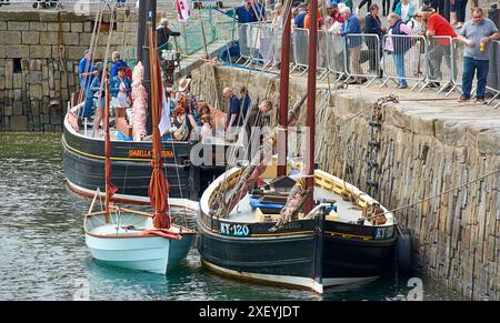 Besucher des Portsoy Boat Festival besuchen und beobachten das Boot Isabella Fortuna Wick, das im alten Hafen vor Anker liegt Stockfoto