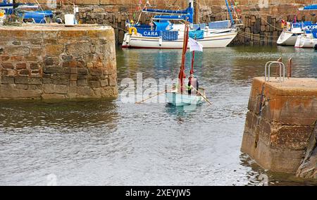 Portsoy Boat Festival kleines Ruderboot mit braunen Segeln, das den Hafen verlässt Stockfoto