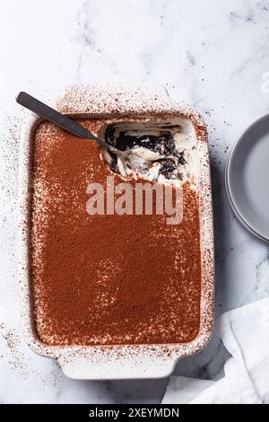 Hausgemachtes Tiramisu mit Schokoladenkeksen in einer Auflaufform auf einem weißen Marmortisch, Blick von oben. Stockfoto