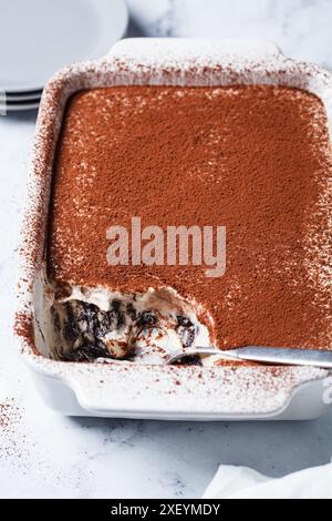 Hausgemachtes Tiramisu mit Schokoladenkeksen in einer Auflaufform auf einem weißen Marmortisch. Stockfoto