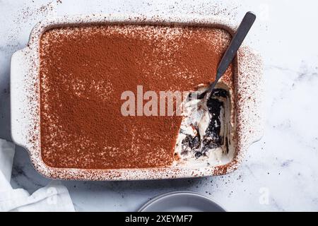 Hausgemachtes Tiramisu mit Schokoladenkeksen in einer Auflaufform auf einem weißen Marmortisch, Blick von oben. Stockfoto