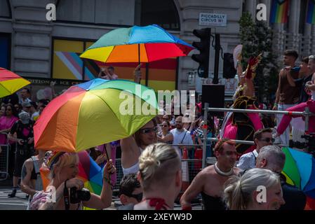 London, Großbritannien. Juni 2024. Partyfreunde tanzen mit großen Regenbogenschirmen während der Pride Parade im Zentrum von London. Die Pride Parade in London feiert die Vielfalt der LGBTQ-Community im Zentrum Londons. Quelle: SOPA Images Limited/Alamy Live News Stockfoto