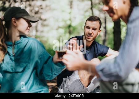 Eine Gruppe von Freunden genießt an einem sonnigen Tag Drinks im Wald Stockfoto
