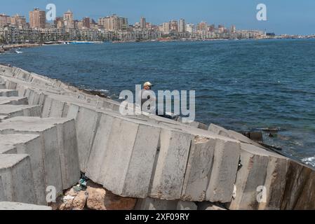 Alexandria, Ägypten. Juni 2024. Ein Mann sitzt allein auf der Betonmündung, einer Barriere für mögliche Überschwemmungen; die ägyptische Mittelmeerstadt ist vom Anstieg des Meeresspiegels bedroht. (Credit Image: © John Wreford/SOPA Images via ZUMA Press Wire) NUR REDAKTIONELLE VERWENDUNG! Nicht für kommerzielle ZWECKE! Stockfoto