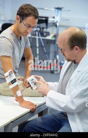Forscher, die multipad-Elektroden im Kontrollarm für das Stimulationsmodell für Sensorsignale platzieren Anwendungen zur Rehabilitation der unteren Extremität/ Stockfoto
