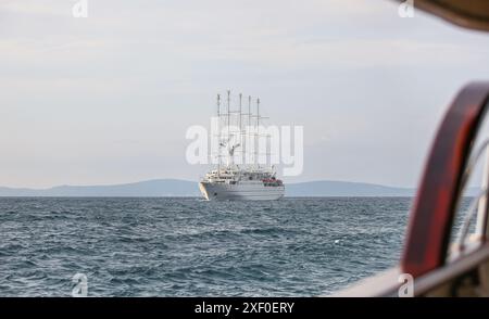 Korčula, Kroatien. 30. Juni 2024: Bei Tagesanbruch segelt das fünf-Masten-Kreuzfahrtschiff WINDSURF, eines der größten Segelschiffe der Welt, in der Adria und nähert sich der Insel Mljet. Das Schwesterschiff des French CLUB MED 2, früher als CLUB MED 1 bekannt, erreicht die Stadt Korcula nahe Dubrovnik an der dalmatinischen Küste. Windstar Cruises, der riesige Besitzer von Staysail-Schonern, hat eine mehrjährige Initiative gestartet, um seine Yachten der Wind-Klasse neu zu gestalten und zu renovieren: Wind Star, Wind Spirit & Wind Surf (Flaggschiff der Flotte), die Arbeiten an letzteren in zwei Phasen Ende 2024 und 2026. Quelle: Kevin Izorce/Alamy Live News Stockfoto