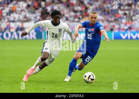 Der Engländer Kobbie Mainoo (links) und der slowakische Stanislav Lobotka kämpfen um den Ball während der UEFA Euro 2024, im Achtelfinale in der Arena AufSchalke in Gelsenkirchen. Bilddatum: Sonntag, 30. Juni 2024. Stockfoto