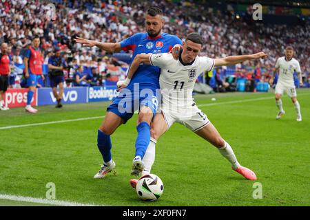 Der Engländer Phil Foden (rechts) und der slowakische Peter Pekarik kämpfen um den Ball während der UEFA Euro 2024, im Achtelfinale in der Arena AufSchalke in Gelsenkirchen. Bilddatum: Sonntag, 30. Juni 2024. Stockfoto