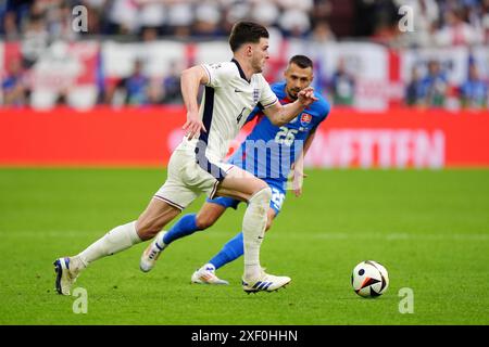 Der Engländer Declan Rice und der slowakische Ivan Schranz kämpfen um den Ball während der UEFA Euro 2024, im Achtelfinale in der Arena AufSchalke in Gelsenkirchen. Bilddatum: Sonntag, 30. Juni 2024. Stockfoto