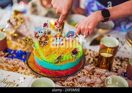 Nahaufnahme der Hände, die zum Piratengeburtstag für die Kinderfeier schneiden. Stockfoto