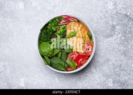 Gesunde Mahlzeit. Köstliches Hühnchen, Gemüse und Spinat in der Schüssel auf hellgrauem Tisch, Blick von oben Stockfoto