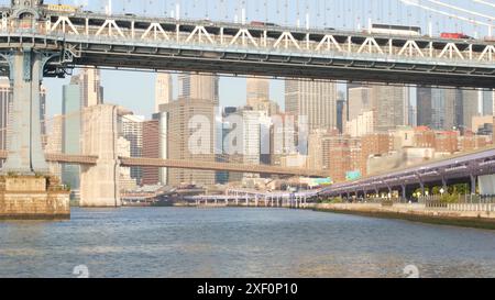New York City Manhattan Bridge nach Brooklyn. Die Skyline der Innenstadt am Wasser, die Wolkenkratzer des Finanzviertels der USA vom Pier 35. Blick auf den East River, Sonnenuntergang am Morgen. Riverfront-Architektur. Stockfoto