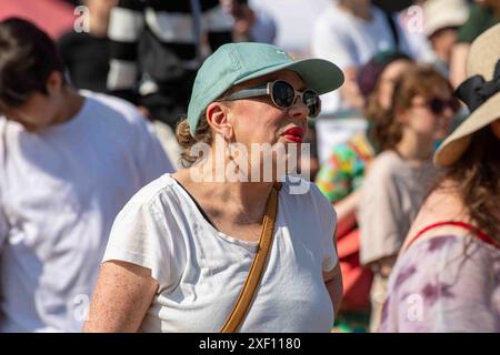 Frau mittleren Alters mit Mütze und Sonnenbrille beim Maailma kylässä oder beim World Village Festival im Stadtteil Suvilahti in Helsinki, Finnland Stockfoto