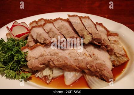 Selektiver Fokus, in Scheiben geschnittenes knuspriges Bauchschwein auf weißem Teller serviert. Stockfoto
