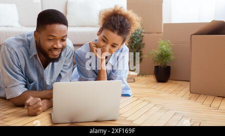 Paare Benutzen Laptop, Der Zwischen Kisten Im Neuen Haus Liegt, Panorama Stockfoto
