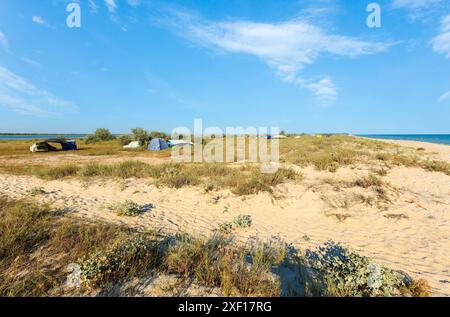 Eigenständiges Camping in sandiger Prärie zwischen dem Ustrychne-See (Austernsee) und dem Asowschen Meer (Lazurne, Region Cherson, Ukraine). Menschen und Autos uRecognii Stockfoto