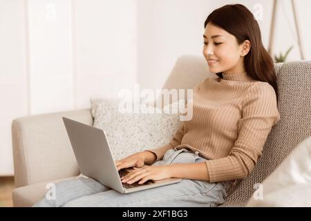 Frau, die im Wohnzimmer an einem Laptop arbeitet Stockfoto