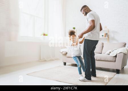 Vater und Tochter tanzen in einem hellen Wohnzimmer Stockfoto