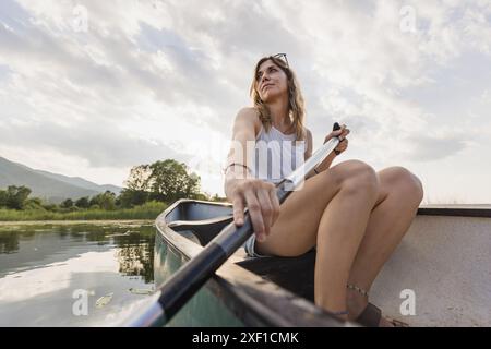 Fröhlich lächelnde Frau, die an einem schönen, ruhigen, sonnigen Sommertag auf einem See Kanu fährt, Nahaufnahme. Urlaubs- und Freizeitkonzepte. Stockfoto