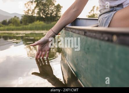 Aktive junge Frau paddelt mit einem Kanu auf einem See umgeben von grüner Sommernatur, Nahaufnahme. Kanu-, Therapie- und Erholungskonzepte. Stockfoto