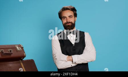 Ein eleganter HotelConcierge mit Gepäck vor der Kamera bietet Gästen ausgezeichneten Service und hilft mit Koffern. Erfahrener, selbstbewusster Türhüter oder Pagen in formeller Uniform. Stockfoto