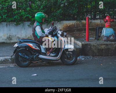 Jakarta, Indonesien - 11. Mai 2024. Er trägt einen grünen Helm und eine grüne Jacke und wartet auf seinen Passagier. Stockfoto