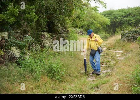 Senior latin man geht auf einem ländlichen Pfad, einem restaurierten königlichen Steinweg, der von Barichara nach Guane in Santander, Kolumbien, führt. Konzept: Aktive Rentner Stockfoto