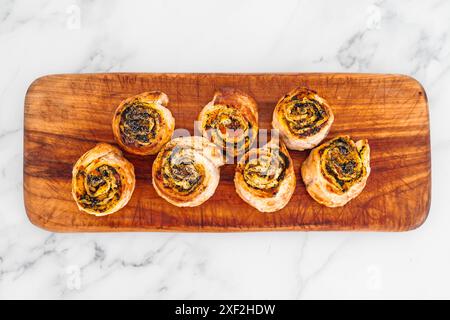 Kürbisspinat- und Käsegebäck-Brötchen auf hölzernem Schneidebrett, frisch gebackene und hausgemachte, gesunde Rezepte Stockfoto