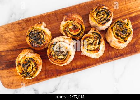 Kürbisspinat- und Käsegebäck-Brötchen auf hölzernem Schneidebrett, frisch gebackene und hausgemachte, gesunde Rezepte Stockfoto