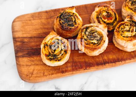 Kürbisspinat- und Käsegebäck-Brötchen auf hölzernem Schneidebrett, frisch gebackene und hausgemachte, gesunde Rezepte Stockfoto