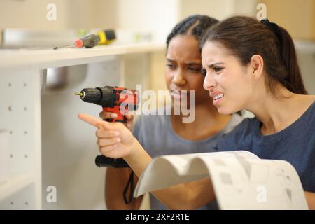 Verwirrte Mitbewohner, die Möbel mit Anleitung in der Küche installieren Stockfoto