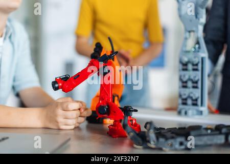 Nahaufnahme von Kindern, die auf einen kleinen Roboter schauen, Robotik in der Grundschule lernen. Junge Schüler bauen Roboter im Robotik-Club nach der Schule. Stockfoto