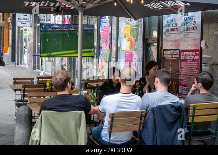 Gäste vor einer Bar in der Kastanienallee in Berlin-Prenzlauer Berg verfolgen das Spiel Türkei gegen Portugal anlässlich des Fußballeuropameisterschaft UEFA EURO 2024. / Gäste vor einer Bar in der Kastanienallee in Berlin-Prenzlauer Berg sehen das Spiel zwischen der Türkei und Portugal anlässlich der Fußball-Europameisterschaft UEFA EURO 2024. UEFA Fußball-Europameisterschaft - Fußballfans *** Gäste vor einer Bar in der Kastanienallee in Berlin Prenzlauer Berg beobachten das Spiel zwischen der Türkei und Portugal anlässlich der Fußball-Europameisterschaft UEFA EURO 2024 Gäste vor der Tür Stockfoto