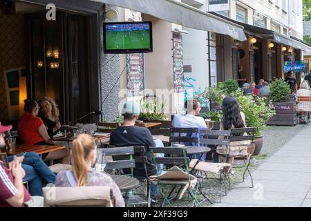 Gäste vor einer Bar in der Kastanienallee in Berlin-Prenzlauer Berg verfolgen das Spiel Türkei gegen Portugal anlässlich des Fußballeuropameisterschaft UEFA EURO 2024. / Gäste vor einer Bar in der Kastanienallee in Berlin-Prenzlauer Berg sehen das Spiel zwischen der Türkei und Portugal anlässlich der Fußball-Europameisterschaft UEFA EURO 2024. UEFA Fußball-Europameisterschaft - Fußballfans *** Gäste vor einer Bar in der Kastanienallee in Berlin Prenzlauer Berg beobachten das Spiel zwischen der Türkei und Portugal anlässlich der Fußball-Europameisterschaft UEFA EURO 2024 Gäste vor der Tür Stockfoto