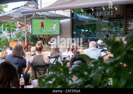 Gäste vor einer Bar in der Kastanienallee in Berlin-Prenzlauer Berg verfolgen das Spiel Türkei gegen Portugal anlässlich des Fußballeuropameisterschaft UEFA EURO 2024. / Gäste vor einer Bar in der Kastanienallee in Berlin-Prenzlauer Berg sehen das Spiel zwischen der Türkei und Portugal anlässlich der Fußball-Europameisterschaft UEFA EURO 2024. UEFA Fußball-Europameisterschaft - Fußballfans *** Gäste vor einer Bar in der Kastanienallee in Berlin Prenzlauer Berg beobachten das Spiel zwischen der Türkei und Portugal anlässlich der Fußball-Europameisterschaft UEFA EURO 2024 Gäste vor der Tür Stockfoto