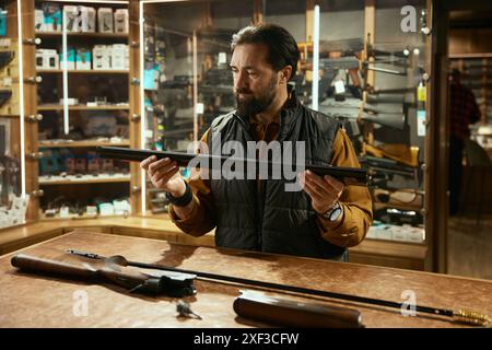 Verkäufer Reinigungspistole mit Ramrod während der Arbeit in der Jagdwerkstatt Stockfoto