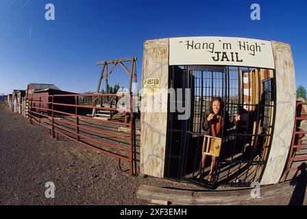 Eine Frau in einer westlichen Stadt hinter alten Gefängnisbars. Stockfoto