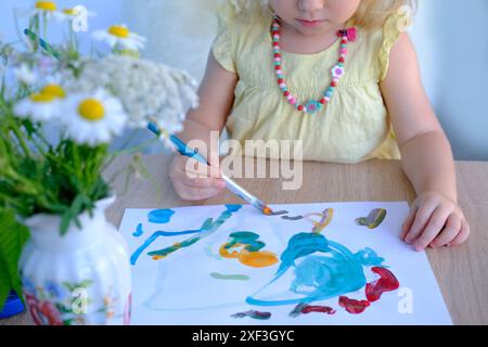 Kinderhandmalerei mit Pinsel, kleines Kind, kleines Mädchen Vorschulkinder 3 Jahre schafft ein helles Bild auf Papier, kindliche naive Zeichnung in farbigem Wasser Stockfoto