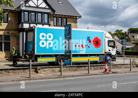 Blauer Koop-Lieferwagen mit Hintertür und Fahrer in Sicht, der vor dem örtlichen Koop-Dorfladen, einem umgebauten Publizisthaus, geparkt ist. Im Village Store Stockfoto