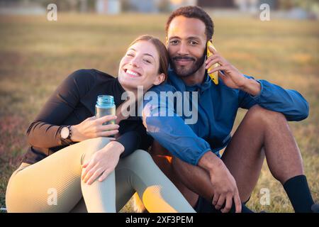 Porträt eines glücklichen jungen Paares mit Smartphone, das bereit ist, im Freien zu trainieren. Stockfoto