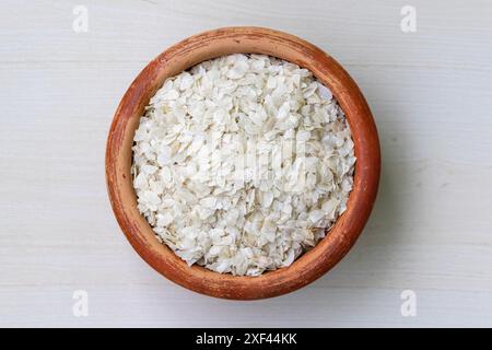 Abgeflachter Reis oder Chira auf einem Erdtopf auf hölzernem Hintergrund. Es ist auch bekannt als poha, pohe, aval, Pauwa, sira, Chivda oder Avalakki. Stockfoto