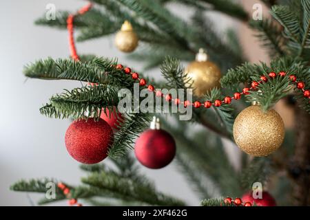 Teil des Weihnachtsbaums, dekoriert mit Girlanden, roten und goldenen Kugeln, Bokeh Stockfoto