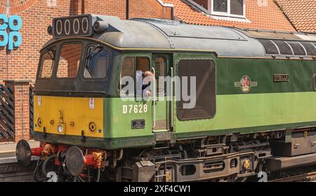 Eine alte Diesellokomotive der North Yorkshire Moors Railway steht östlich eines Bahnhofs. Der Fahrer lehnt sich aus der Kabine. Stockfoto