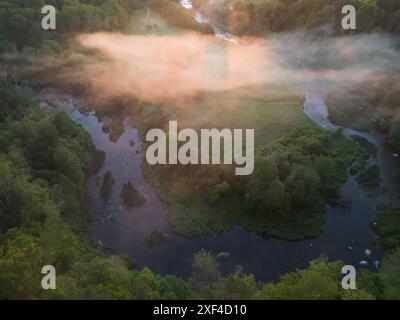 Natur Estlands, Blick von einer Drohne. Ein Pirita-Fluss fließt an einem Sommerabend durch den Wald, ein leichter Nebel in der Luft. Stockfoto