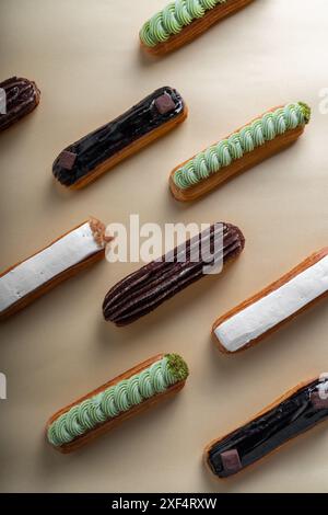 Eclairs Auswahl, verschiedene köstliche Eclairs auf Beige Hintergrund Stockfoto