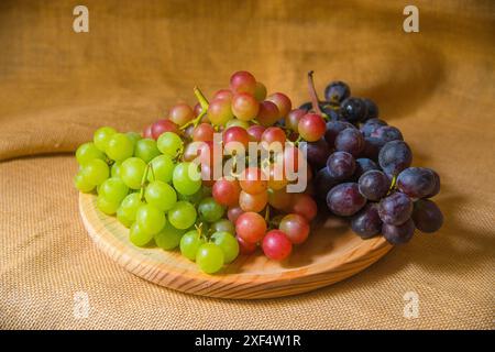 Bunches of three colors grapes on wooden dish. Stockfoto