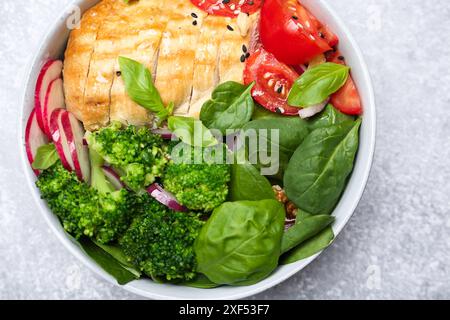 Gesunde Mahlzeit. Köstliches Hühnchen, Gemüse und Spinat in der Schüssel auf hellgrauem Tisch, Blick von oben Stockfoto